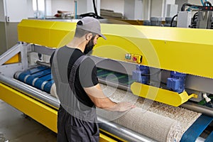 Man operating carpet automatic washing machine in professional laundry service