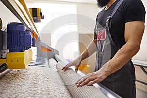 Man operating carpet automatic washing machine in professional laundry service