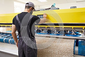 Man operating carpet automatic washing machine in professional laundry service