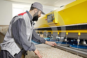 Man operating carpet automatic washing machine in professional laundry service