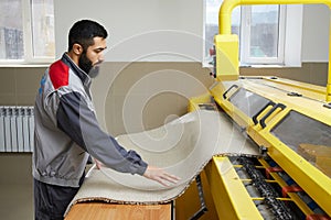 Man operating carpet automatic washing machine in professional laundry service