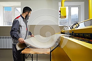 Man operating carpet automatic washing machine in professional laundry service