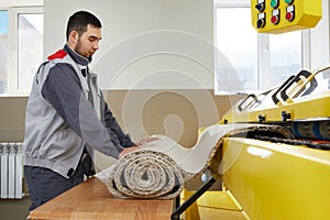 Man operating carpet automatic washing machine in professional laundry service