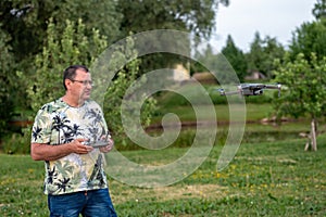 A man operating the drone by remote control on the meadow