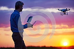 Man operating of flying drone at sunset