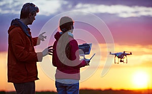 Man operating of flying drone at sunset