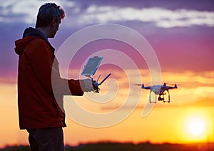 Man operating of flying drone at sunset