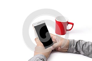 Man operating phone. A red cup sitting on the table