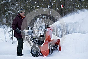 Man Operating Snow Blower on a Stormy Winter`s Day