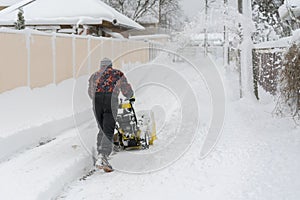 Man operating snow blower to remove snow on driveway. Man using a snowblower. A man cleans snow from sidewalks with snowblower