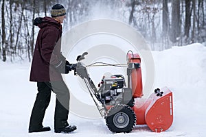 Man Operating Snow Thrower in Driveway