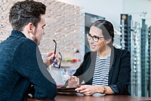 Man in optician shop getting advice from saleswoman