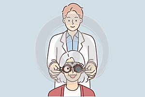 Man optometrist putting on ophthalmic glasses on elderly female patient during vision treatment