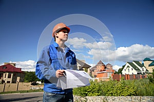 Man in a orange helmet with the plan of construction