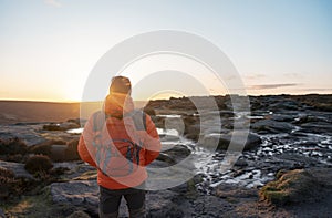 Man in orange jacket relaxing alone on the top of mountain and drinking hot coffee at sunrise. Travel Lifestyle