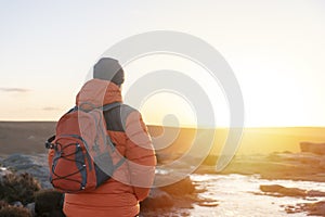 Man in orange jacket relaxing alone on the top of mountain and drinking hot coffee at sunrise. Travel Lifestyle