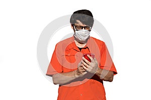 Man with orange shirt and surgical mask while using smarthpone t
