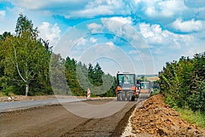 a man in orange suit prepares the road to pits repair with the help of a blower