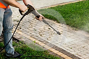 A man in an orange vest cleans a tile of grass in his yard. High pressure cleaning