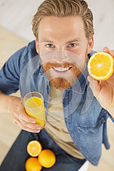 man with oranges drinking orange juice at table