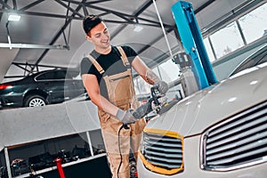 Man with orbital polisher in repair shop polishing car