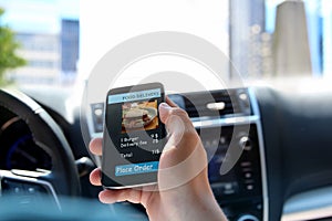 Man is ordering food on the internet using an app while standing in a traffic jam