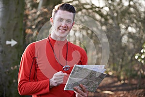 Man Orienteering In Woodlands With Map And Compass photo