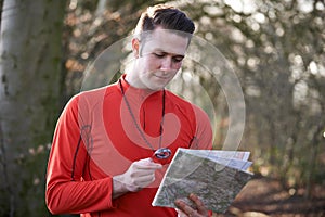 Man Orienteering In Woodlands With Map And Compass photo