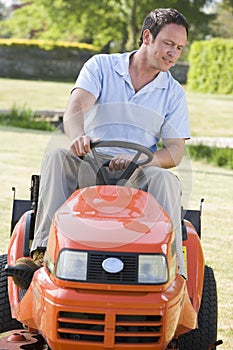 Man outdoors driving lawnmower