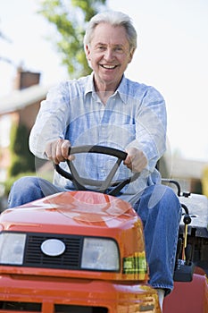 Man outdoors driving lawnmower smiling