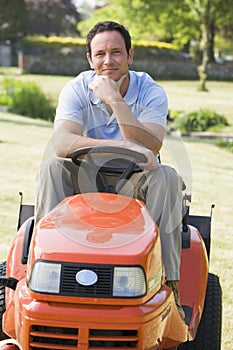 Man outdoors on lawnmower smiling