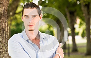 Man outdoors leaning on a tree