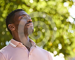 Man Outdoors Relaxing In Countryside Closing Eyes And Breathing Deeply Enjoying Calm Of Nature photo