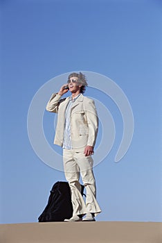 Man outdoors with suitcase using cellular phone