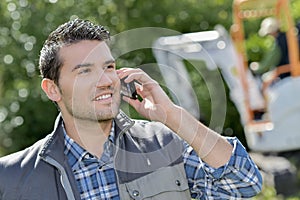 Man outdoors on telephone digger in background