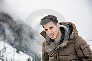 Man in outerwear sitting while looking at camera