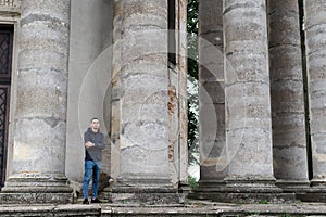 A man outsized by huge pillars of an ancient structure.