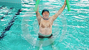 Man over 60 working out with a noodle in the swimming pool