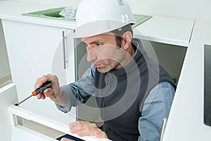 man in overall repairing cabinet