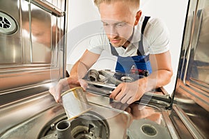 Man In Overall Repairing Dishwasher