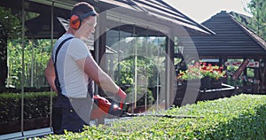 Man in overalls cutting bushes during sunny day