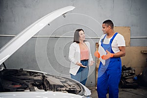 Man in overalls talking to a client about a car repair