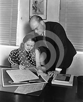 Man overseeing woman signing document