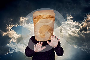 Man with a package on his head on a stormy sky background. The man is looking for a blind road