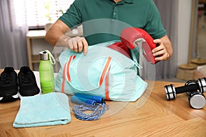Man packing sports bag for training indoors