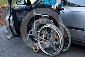 Man packing wheelchair into a car