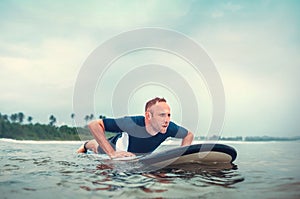 Man padding to line up on the surf board. Active holidays spending concept