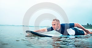 Man padding to line up on the surf board.  Active holidays spending concept photo