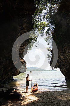 Man with a paddle standing next to sea kayak at secluded beach in Krabi, Thailand