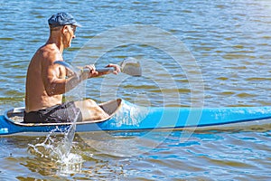 Man paddling a blue and yellow kayak on the river near the shore. Kayaking concept.A man swims in a canoe on the river. A man in a